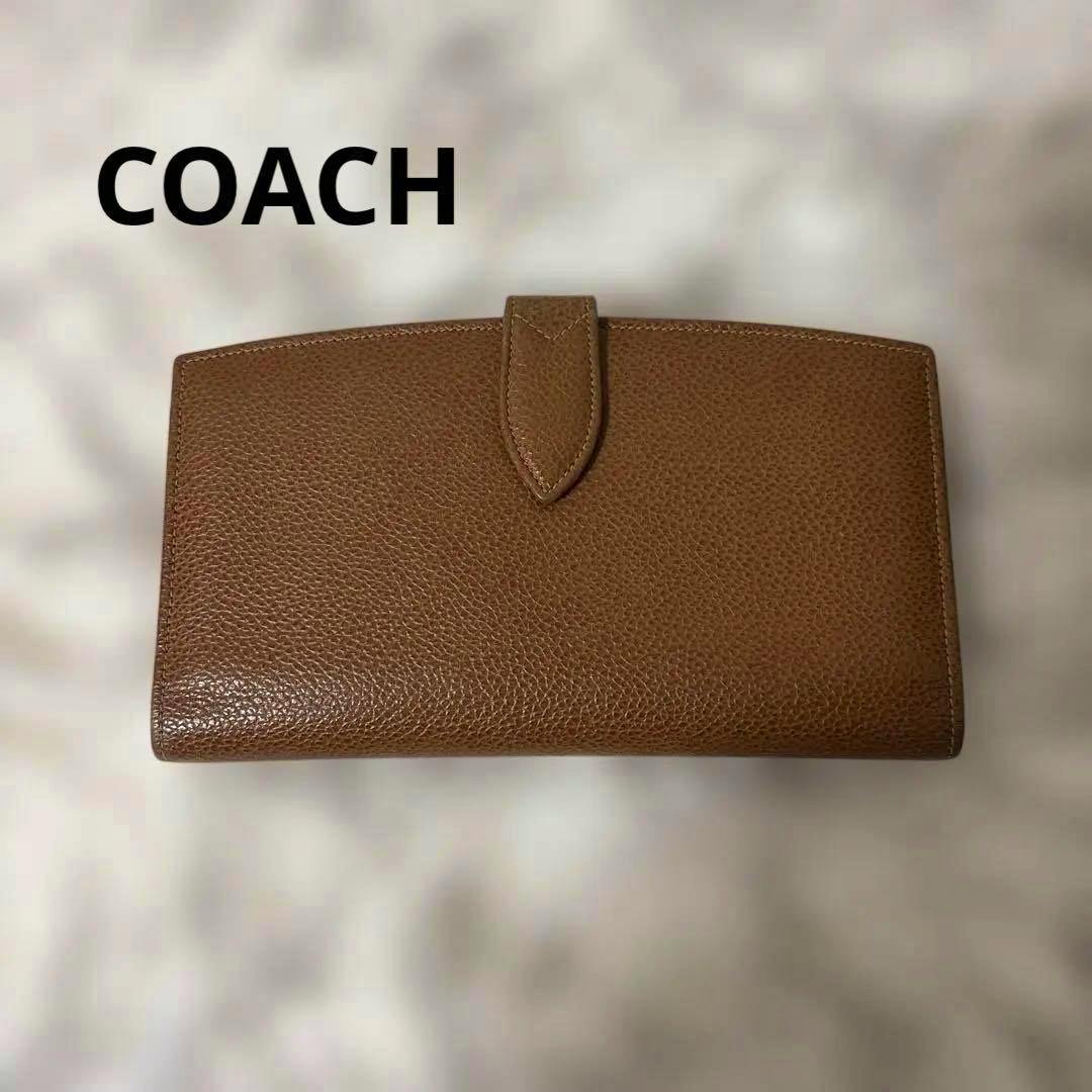 Brown leather long Coach wallet with a tab closure shown flat on a light background.