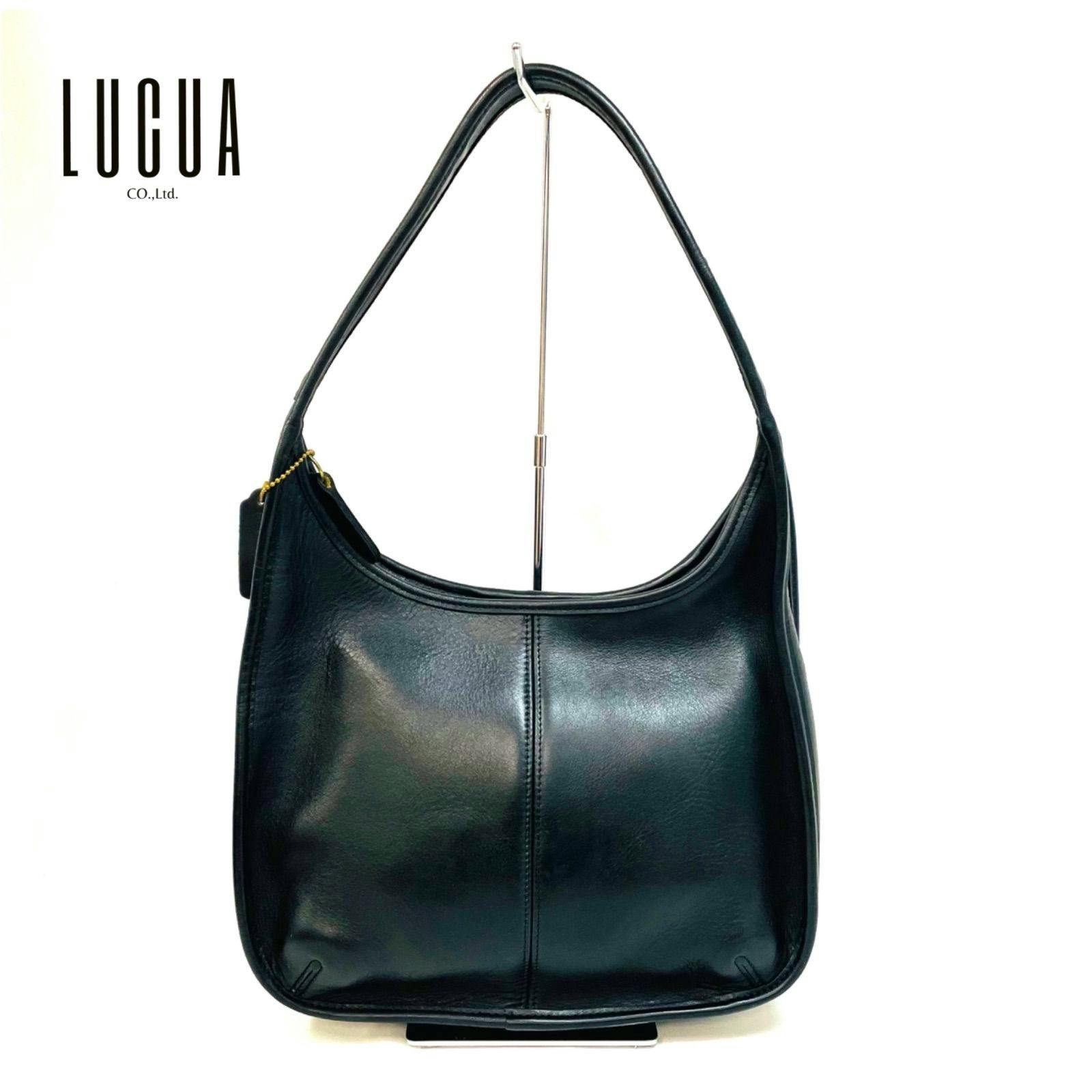Front view of a black Coach leather one-shoulder bag hanging on a display stand.