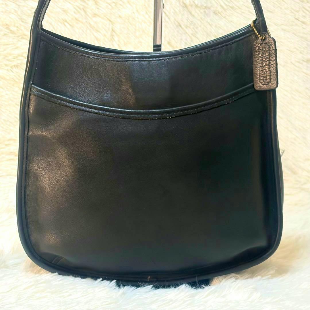 Front view of a black Coach leather one-shoulder bag showing its front panel and attached leather tag.
