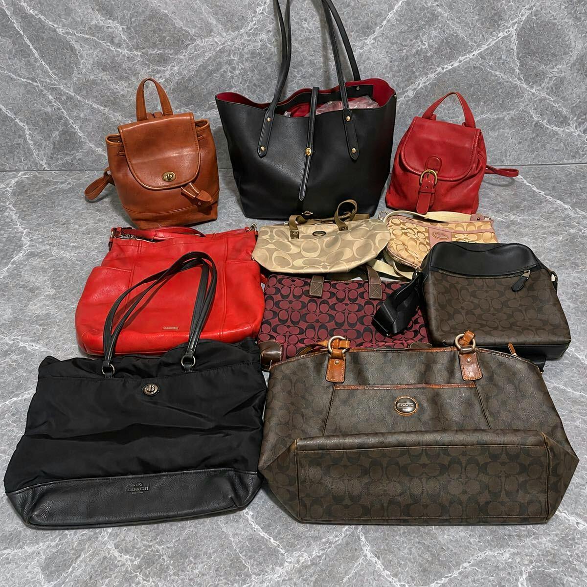 Multiple COACH leather handbags and backpacks from the lot arranged on a gray marble surface.