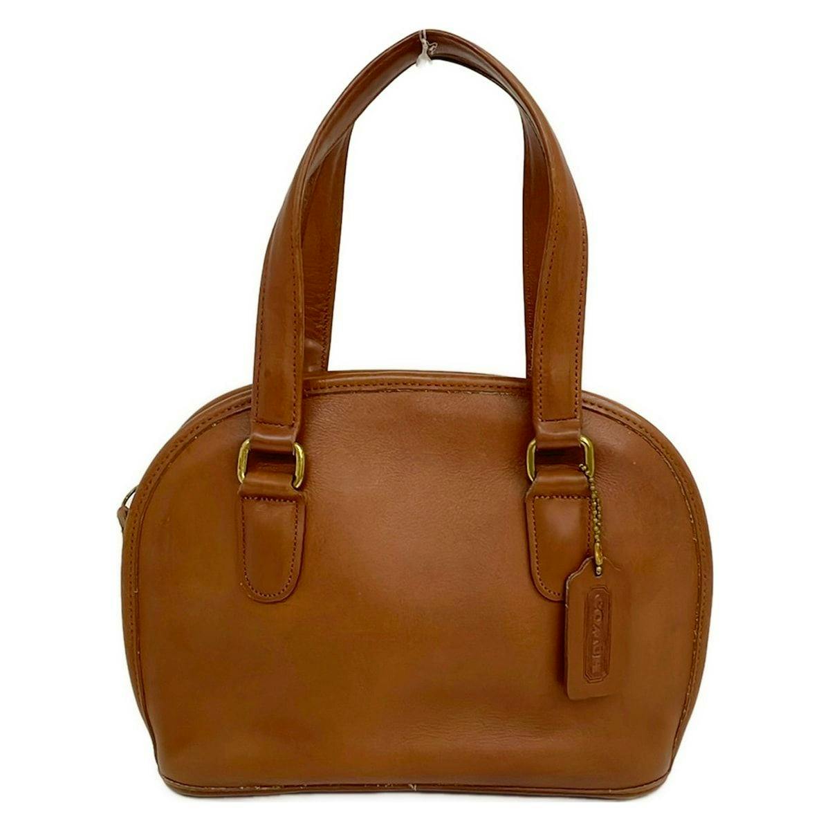 Front view of a brown COACH leather handbag with double handles and a leather tag.