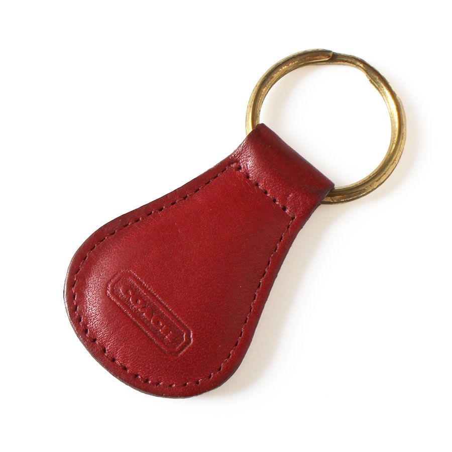 Red leather Coach keychain with a gold key ring on a white background.