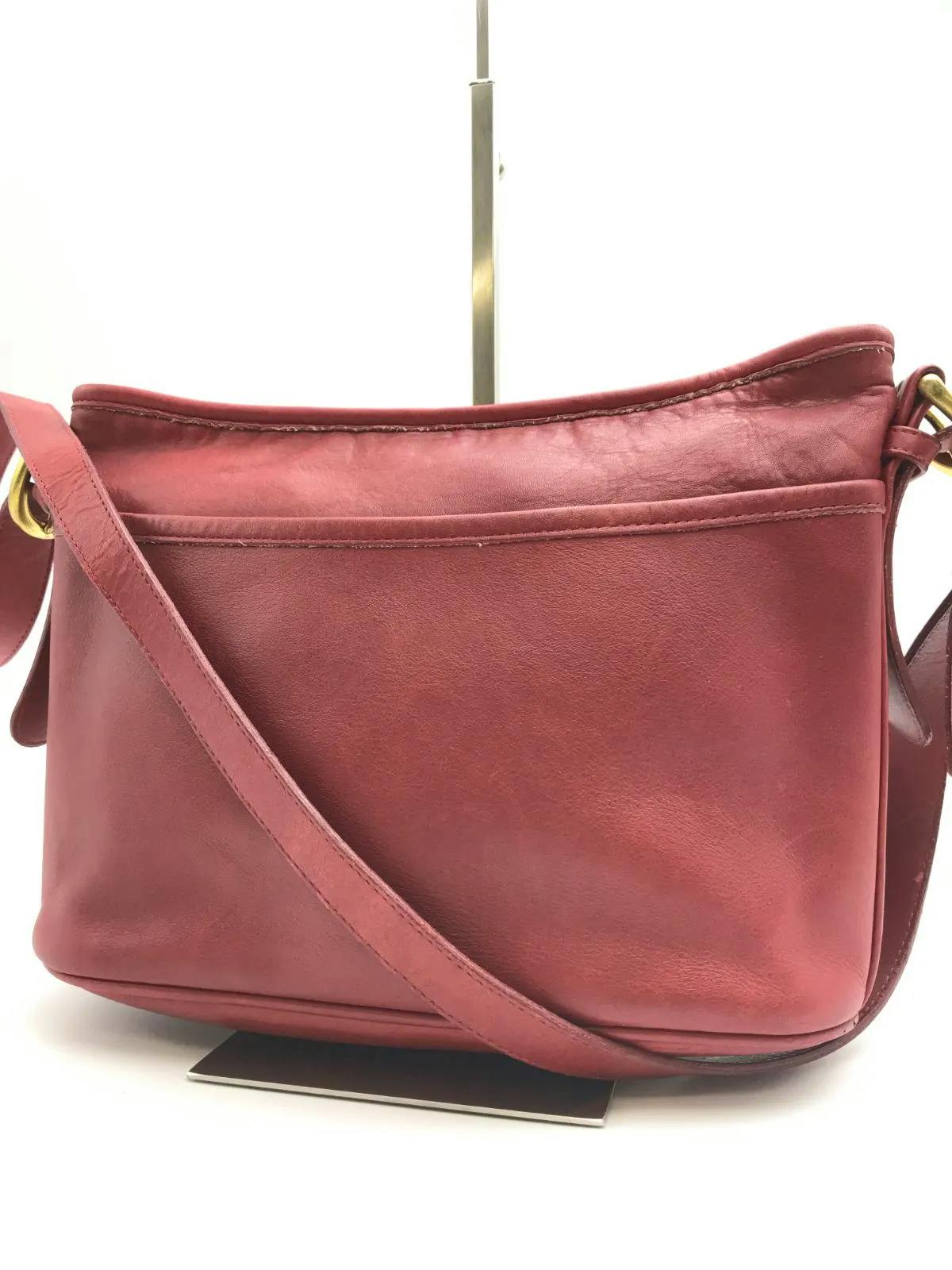 Red leather COACH shoulder bag shown front-facing with strap and front pocket visible.