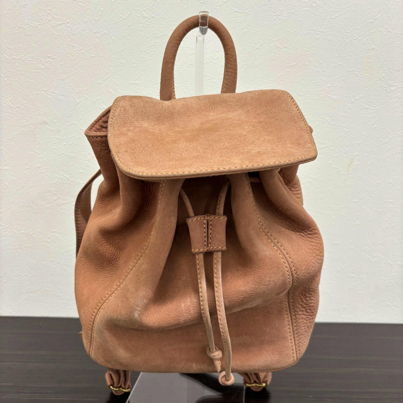 Front view of the Coach pink-beige nubuck suede backpack showing the flap and drawstring closure.