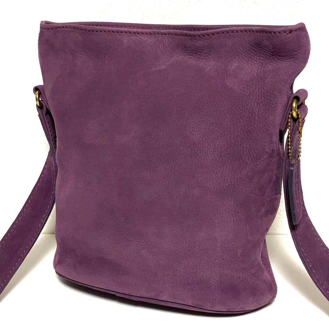 Front view of a purple COACH nubuck leather shoulder handbag shown on a white background.