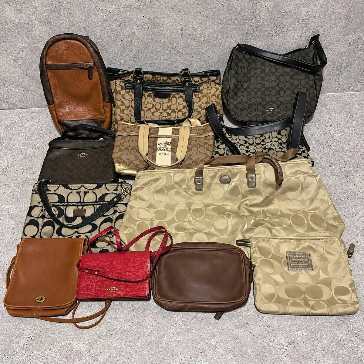 A group of COACH bags and small purses arranged on a floor showing signature C patterns and various colors.