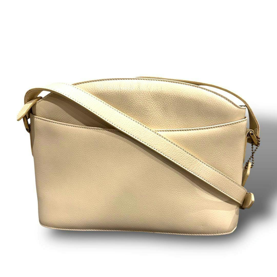 White leather Coach shoulder crossbody bag shown from the back with the strap draped across the front.