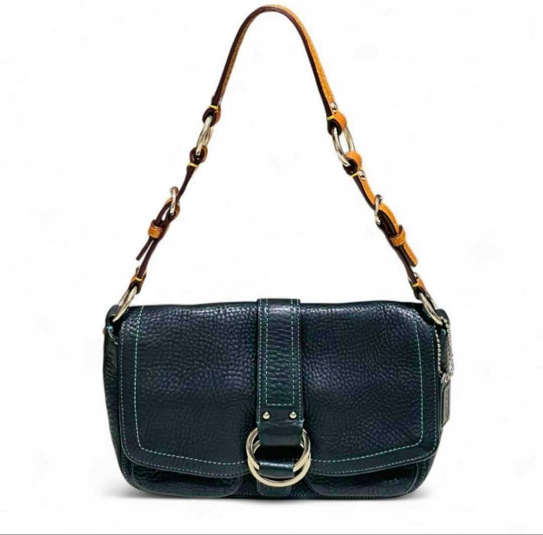 Front view of the COACH one-shoulder black pebbled leather bag showing the front flap, decorative ring detail, and short shoulder strap.