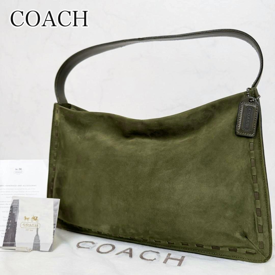 Green nubuck COACH one-shoulder bag on a white background with a Coach hang tag and dust bag visible.