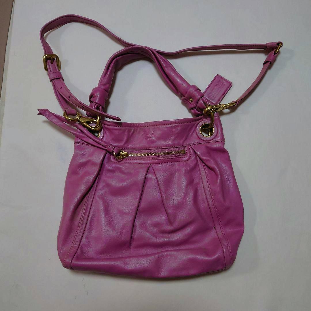 Pink COACH 2-way shoulder bag in synthetic leather laid flat showing gold hardware and straps.