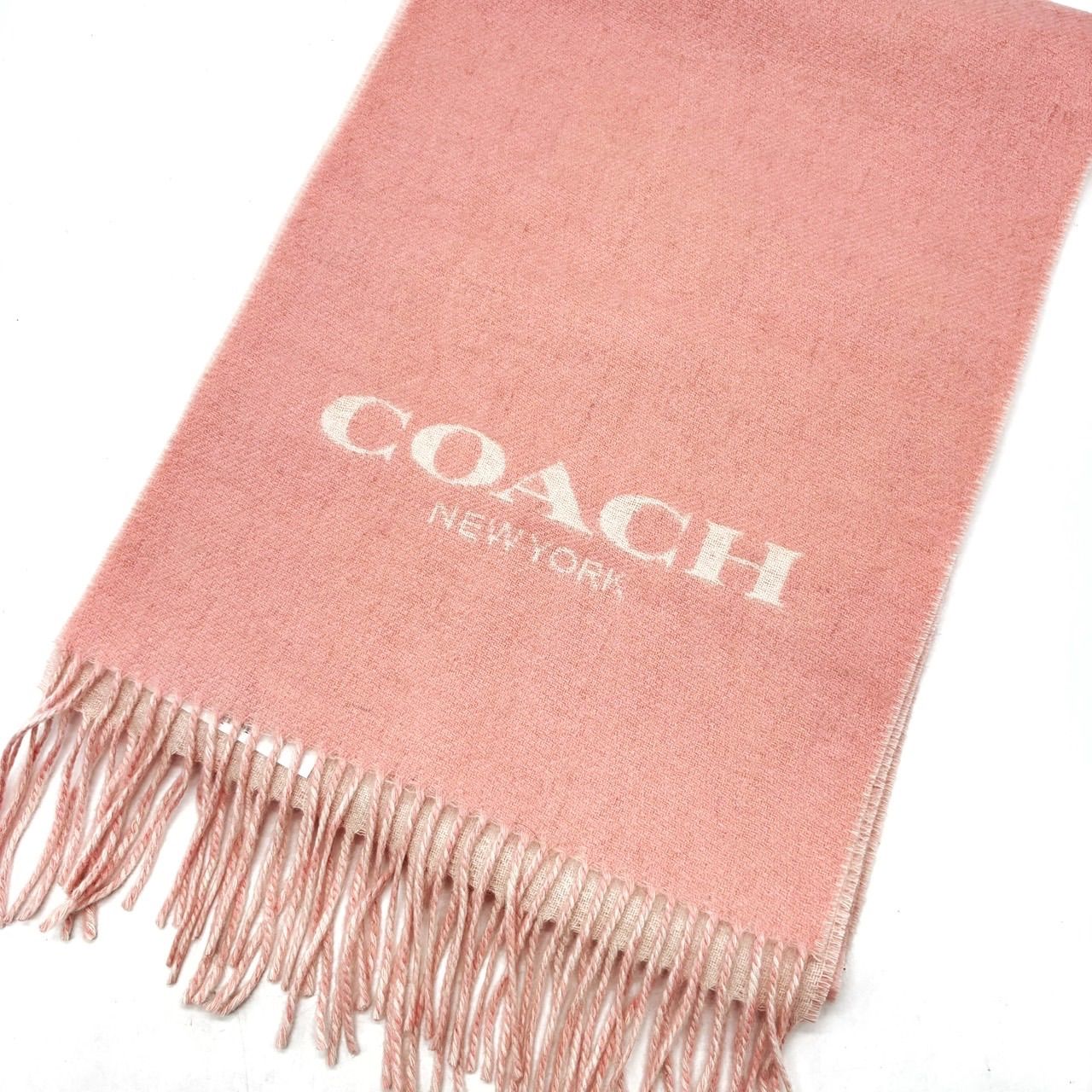Pink-beige Coach wool-cashmere mix scarf laid flat showing fringed ends and COACH NEW YORK logo.