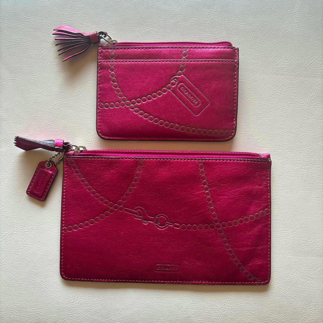 Two pink Coach leather pouches (a small coin/pass case and a larger zip pouch) laid flat on a light surface.