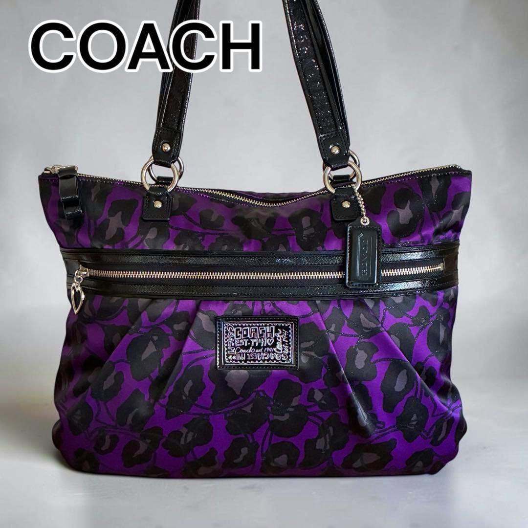 Purple Coach tote bag with black ocelot poppy pattern, black handles, and a front zip pocket.