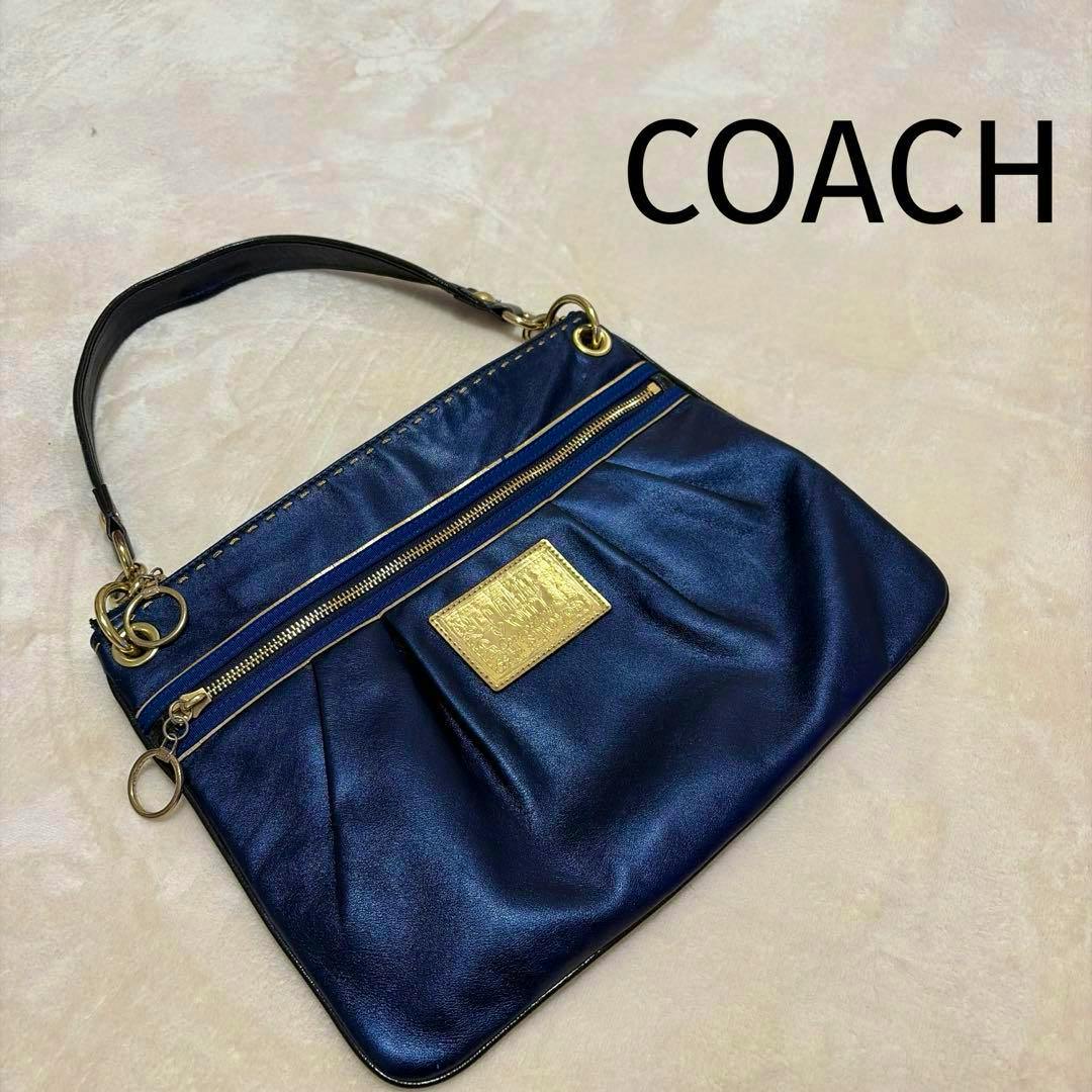 Navy COACH Poppy shoulder bag with gold hardware laid flat on a light surface.