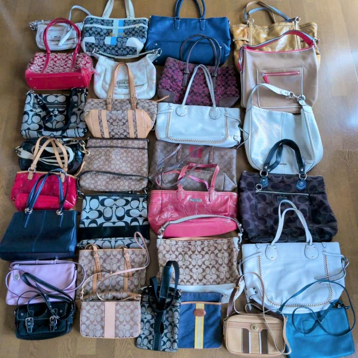 Top-down photo of many Coach signature and Poppy canvas handbags, totes, and shoulder bags arranged on a floor.