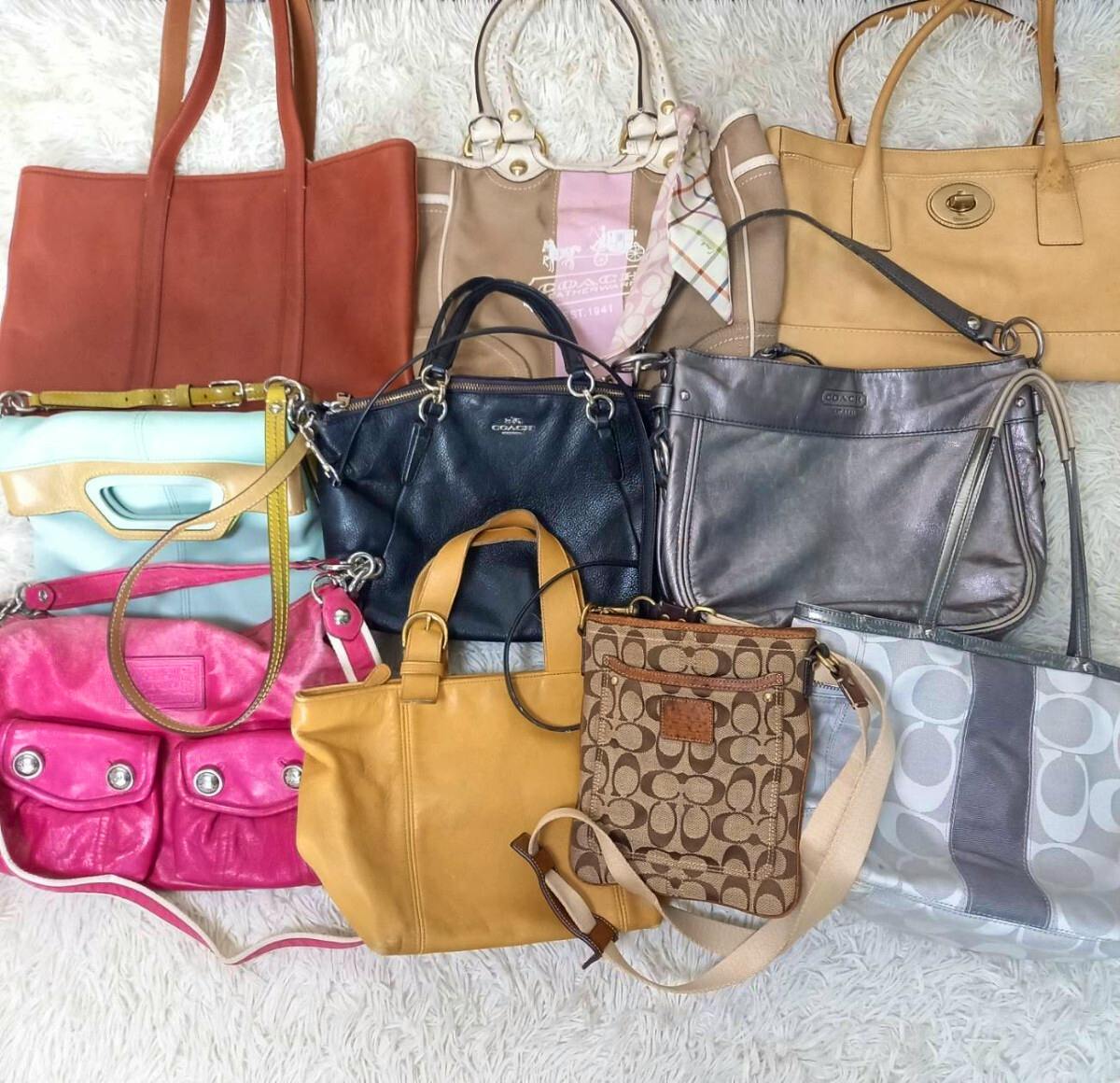 Ten assorted COACH handbags and shoulder bags in various colors arranged on a white rug.