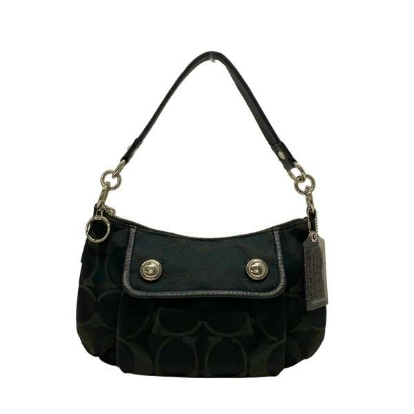 Front view of a black Coach handbag with signature pattern, short shoulder strap, a front flap with two metal buttons, and a hanging tag.