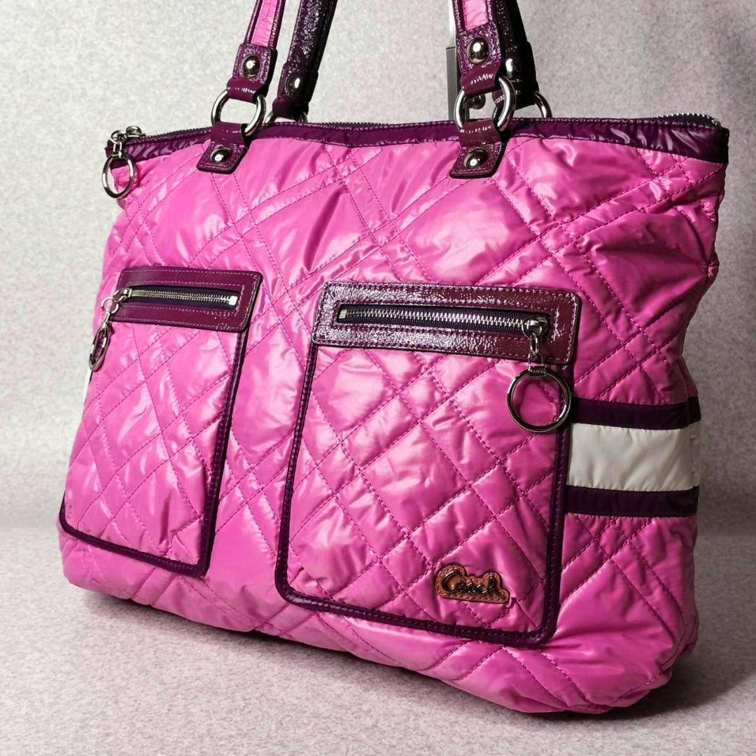 Pink quilted Coach Poppy Ski Bunny Glam tote bag showing two front zip pockets, dark trim, and metal ring zipper pulls.
