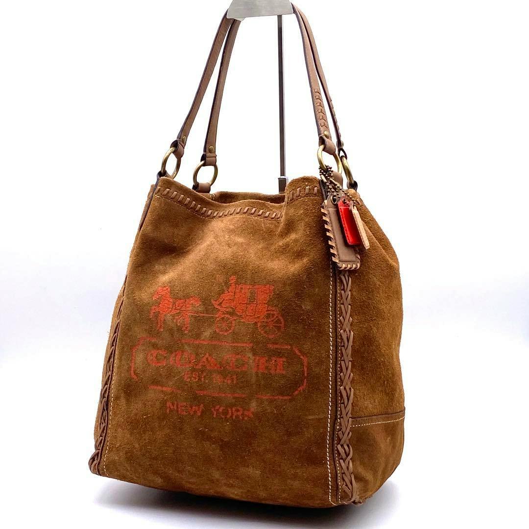 Brown suede Coach Poppy whipstitch tote with leather handles and red Coach logo print on a white background.