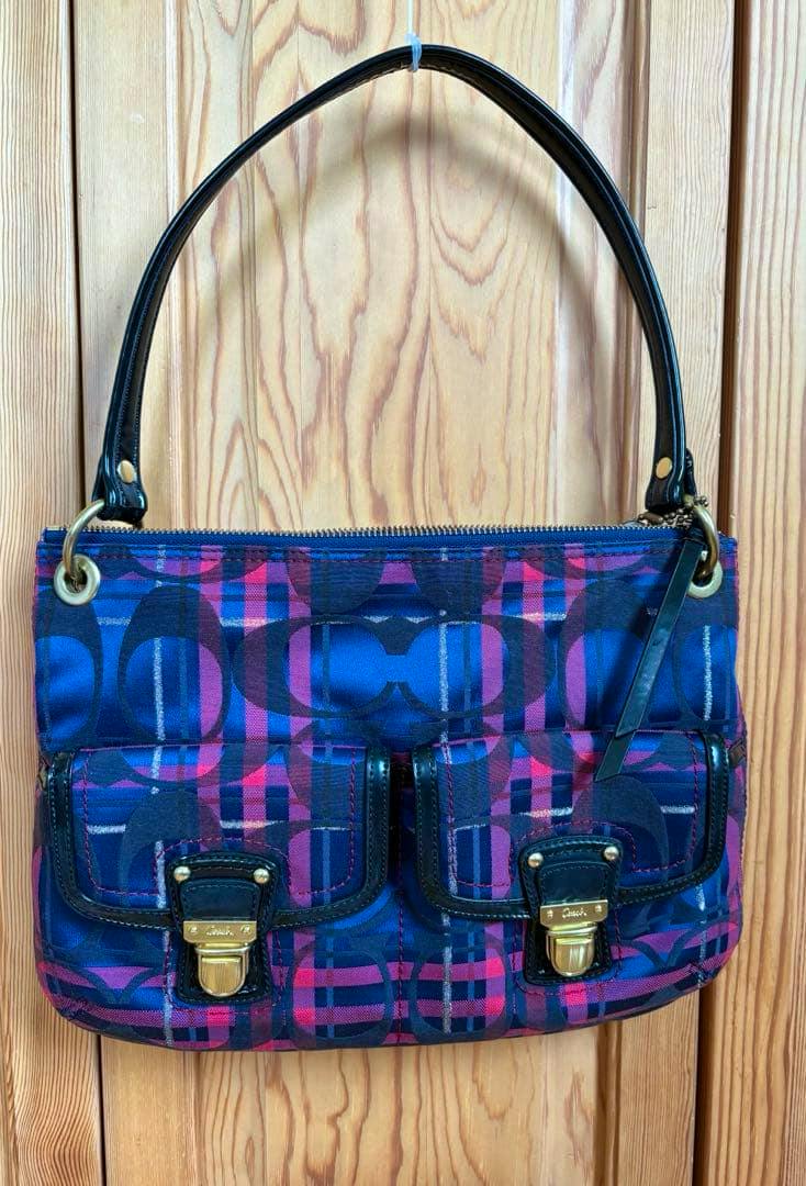 Front view of the Coach Y2K 2-way shoulder bag in poppy pink patterned fabric with two front pockets, gold hardware, and a black leather handle.