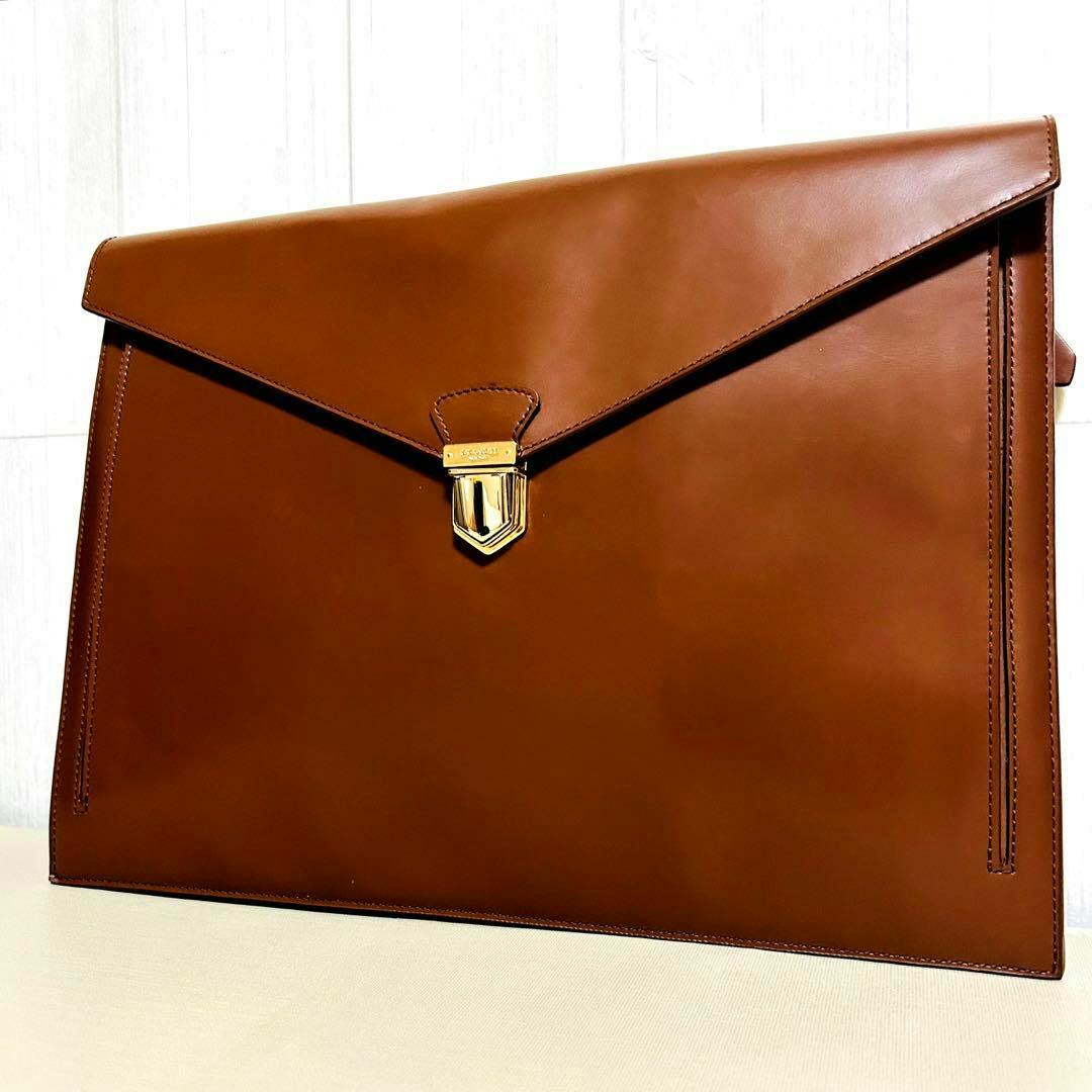 Front view of a brown leather Coach portfolio clutch bag with an envelope flap and gold-tone clasp.