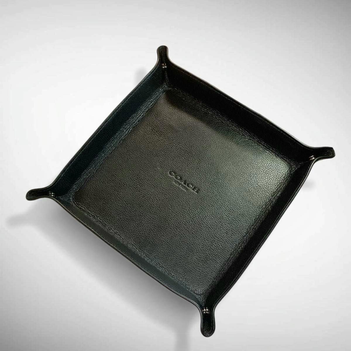 Black leather COACH valet tray viewed from above showing the embossed COACH logo.