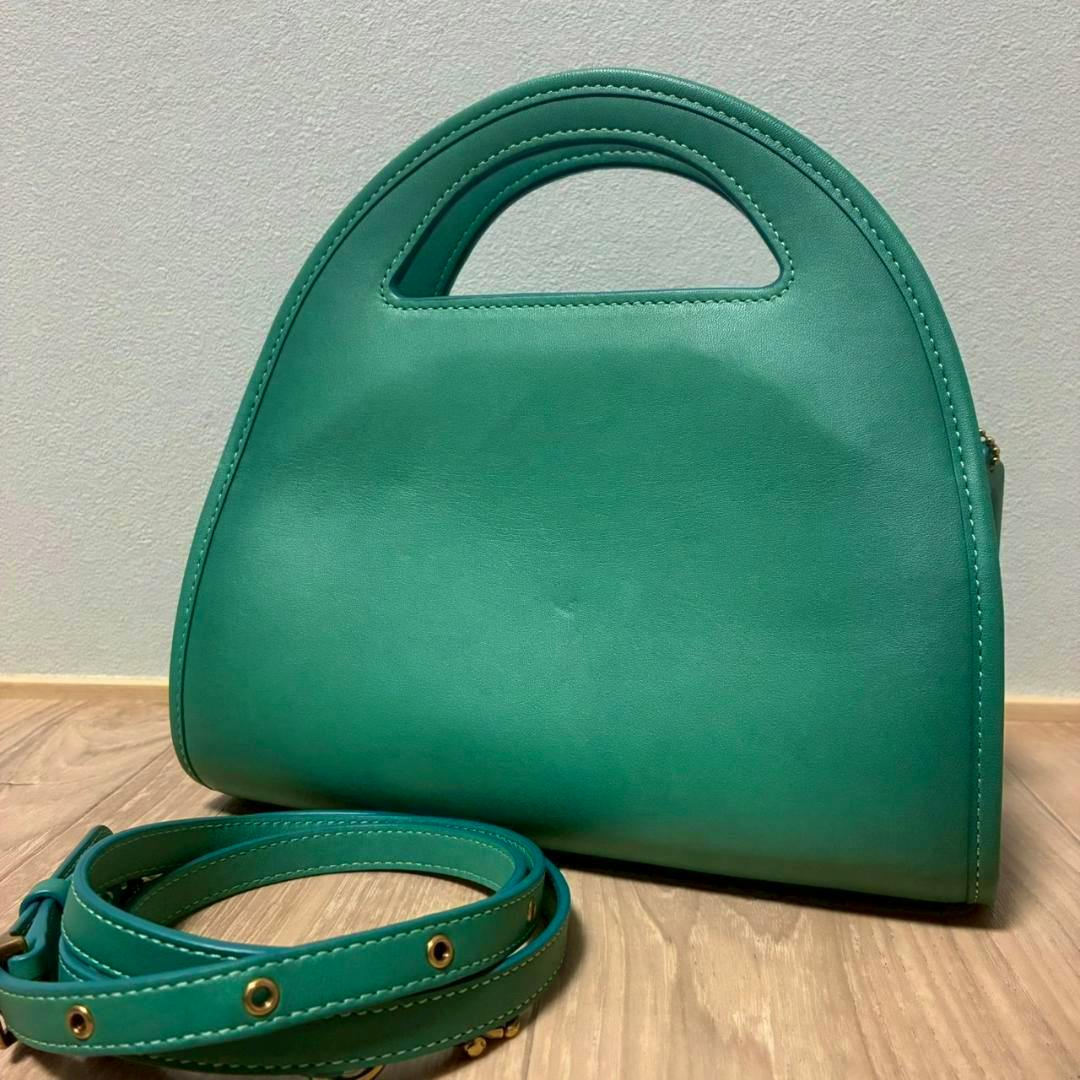 COACH green half-moon 2way cow leather bag shown with a matching shoulder strap coiled in front.