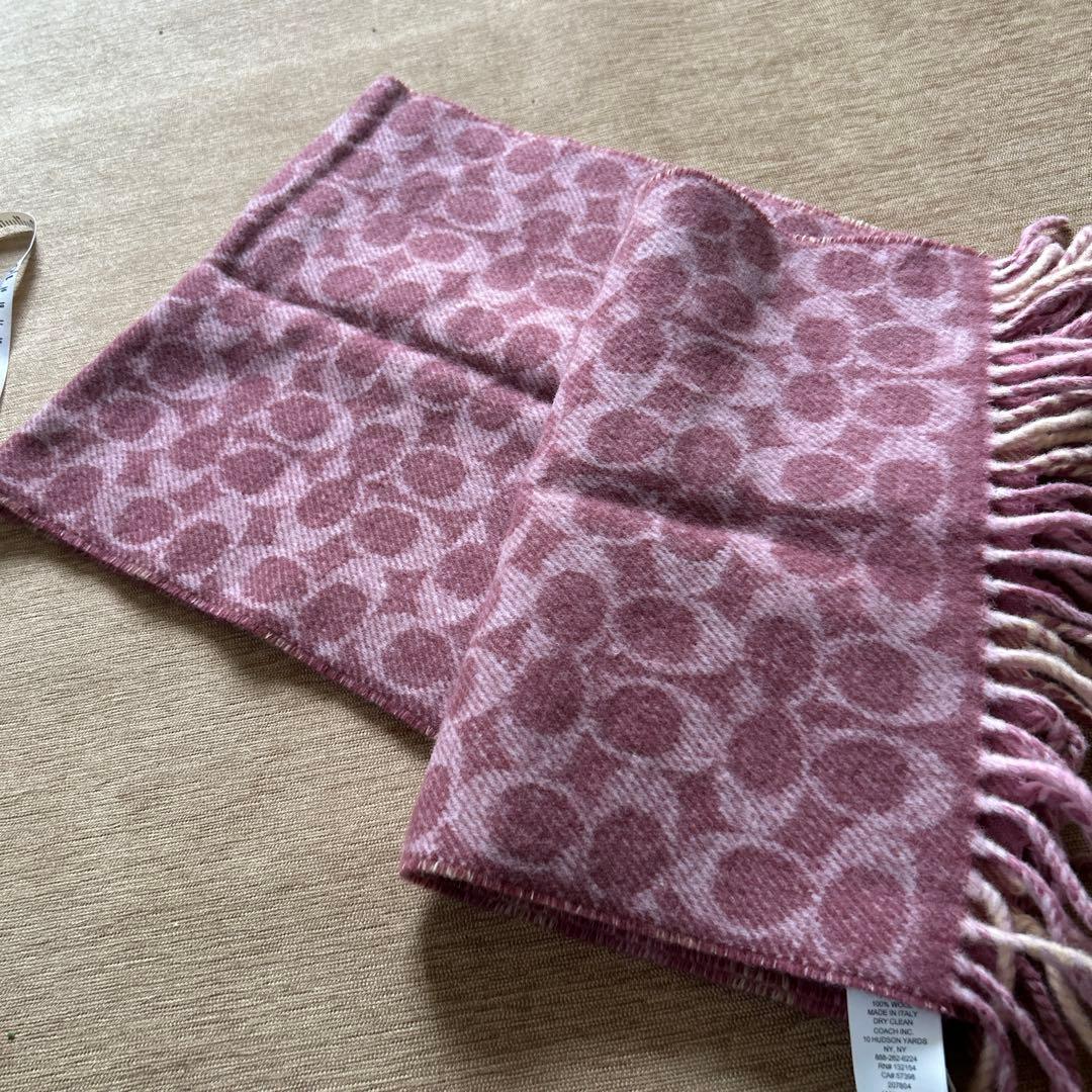 Pink wool reversible scarf laid flat showing a pink circular signature pattern and fringed end.