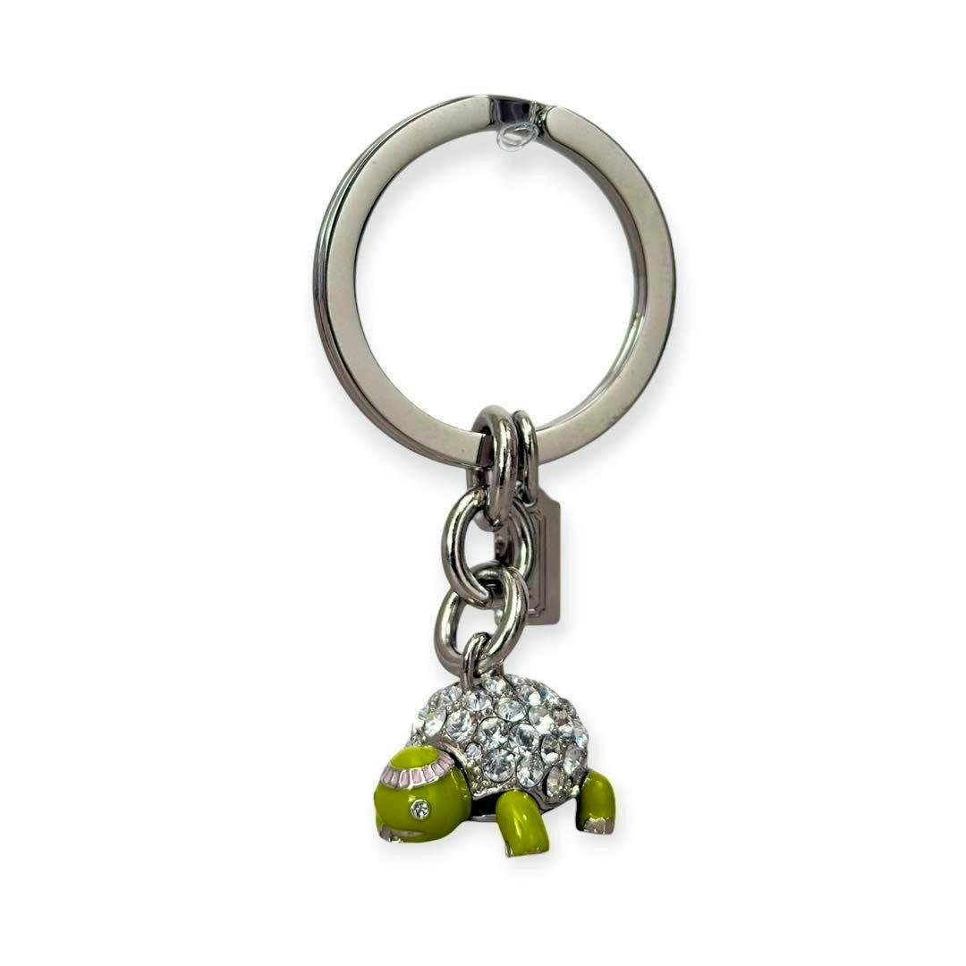 Silver key ring with a green turtle rhinestone COACH bag charm and small tag.