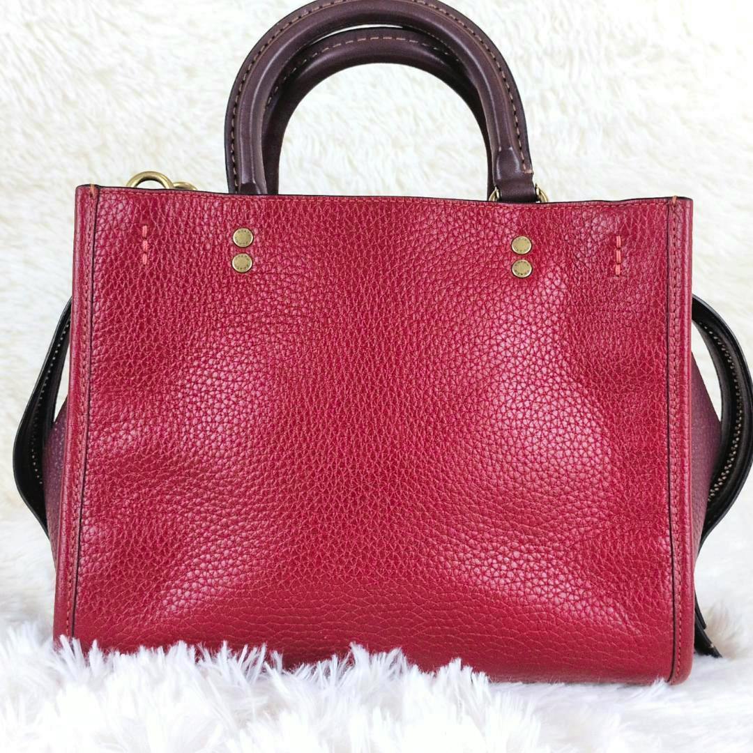 Front view of a red pebbled leather COACH Rogue 25 3-way handbag with top handles on a white background.
