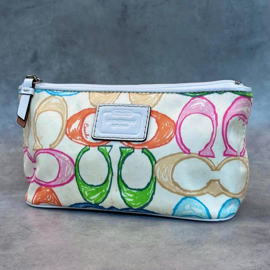 Front view of a multicolor COACH scribble signature nylon cosmetic pouch with a white leather logo patch and top zipper.