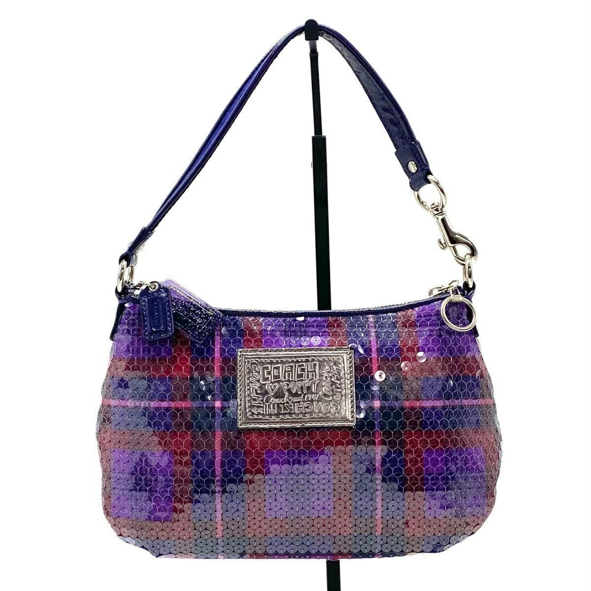 Front view of a purple sequin Coach canvas and leather accessory pouch with a metal logo plaque and short shoulder strap.