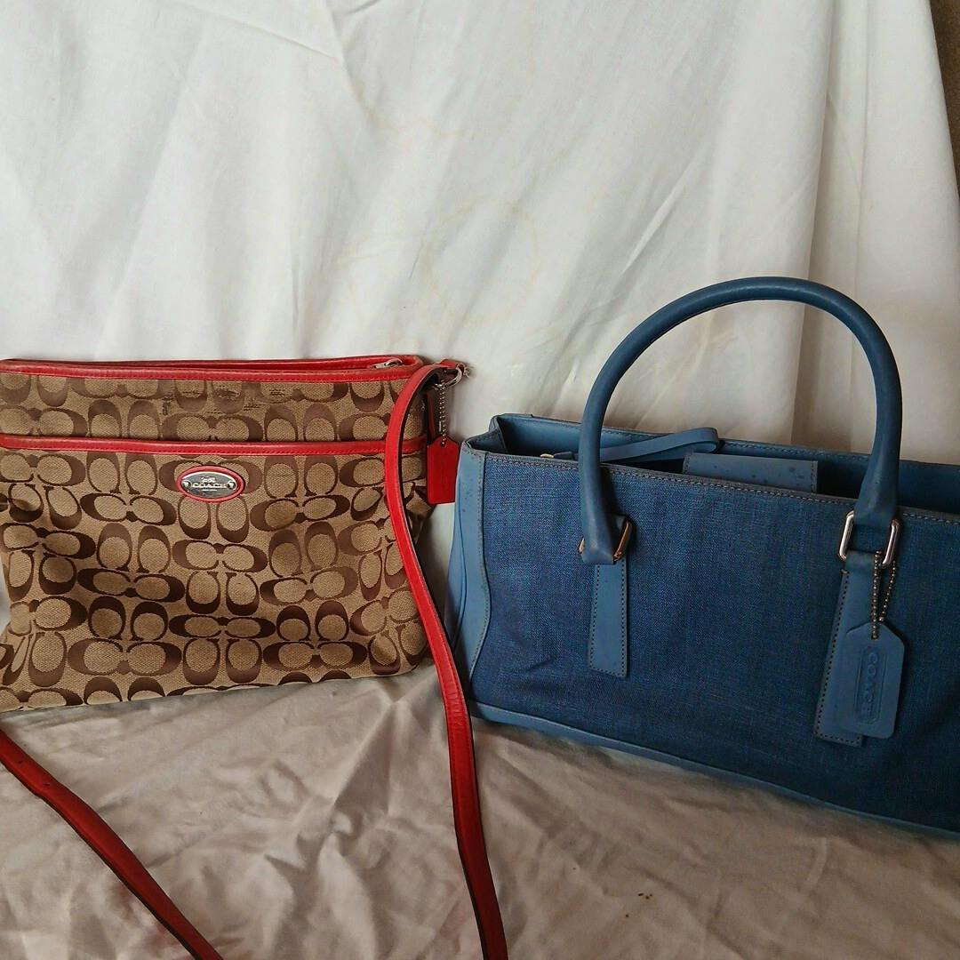 Two COACH bags shown together: a brown signature-pattern shoulder bag with red trim on the left and a blue handbag with handles on the right against a white backdrop.