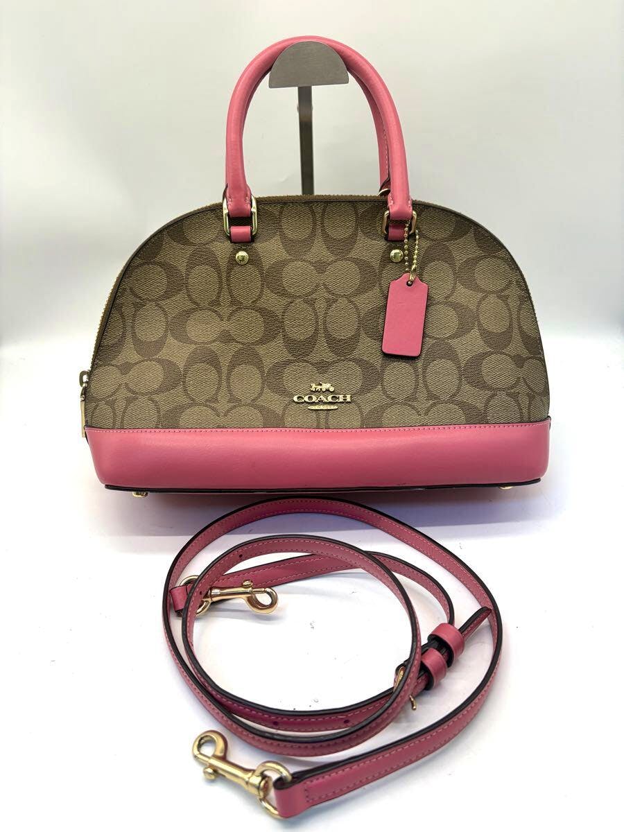 Front view of the COACH signature pink and brown canvas 2-way handbag with pink leather trim, gold hardware, and a detached pink shoulder strap.