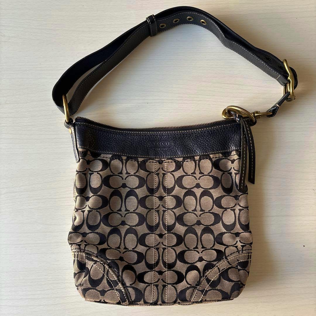 Canvas Coach signature shoulder bag with brown/black 'C' monogram and dark leather trim and strap, shown lying flat.