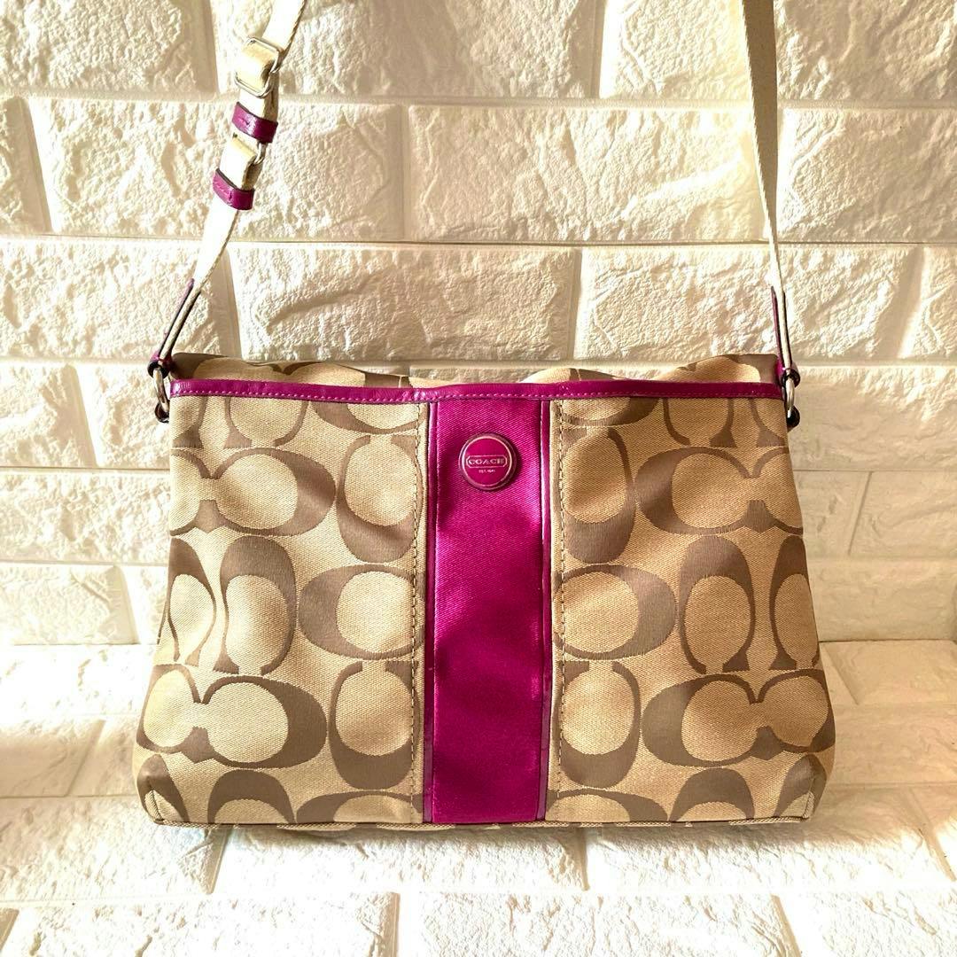 Front view of a Coach signature canvas shoulder bag in tan with a pink center panel and an adjustable shoulder strap.