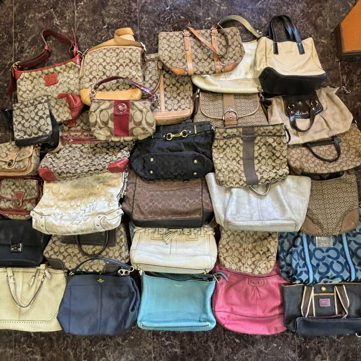 Multiple COACH signature canvas and leather handbags and totes arranged together on a floor.