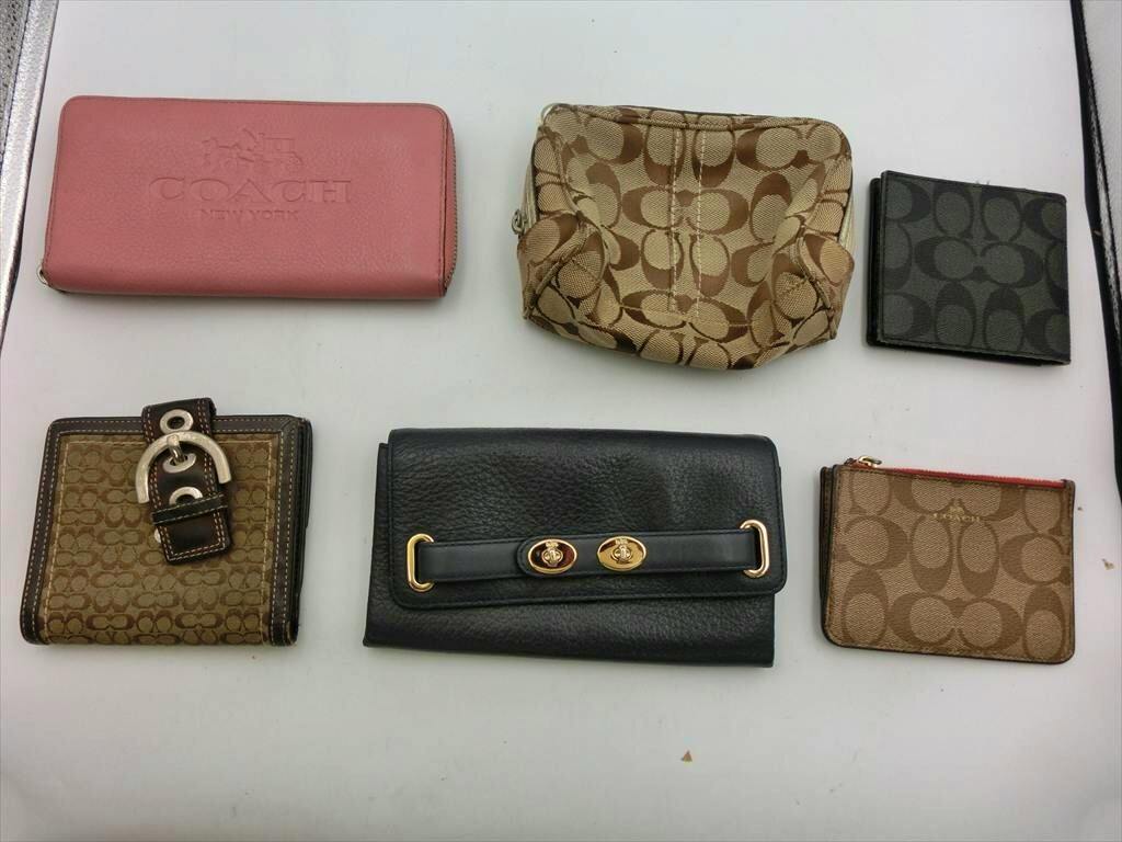 Six COACH wallets and pouches arranged on a white surface, showing signature canvas and leather styles.