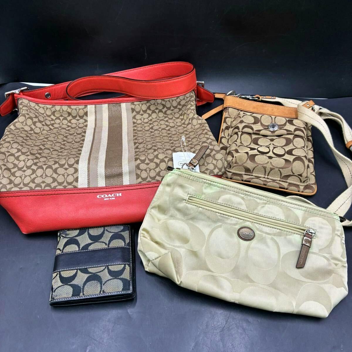 Four Coach signature canvas items arranged on a dark background: a brown shoulder bag with red trim, a small brown crossbody pouch, a light beige zip pouch, and a dark signature bifold wallet.