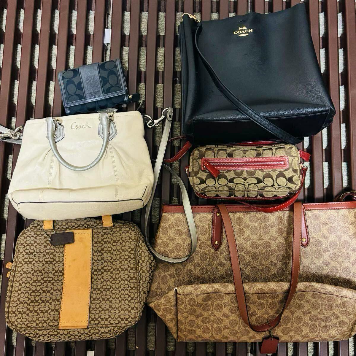 Overhead shot of multiple COACH bags and wallets laid flat, showing signature canvas and leather styles.