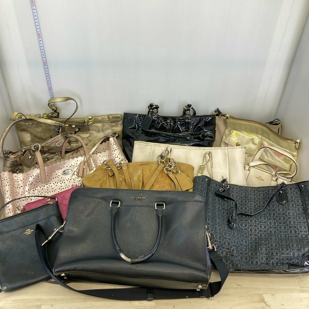 Photo of a set of COACH bags (business bags, tote bags, and shoulder bags) arranged together on a floor.