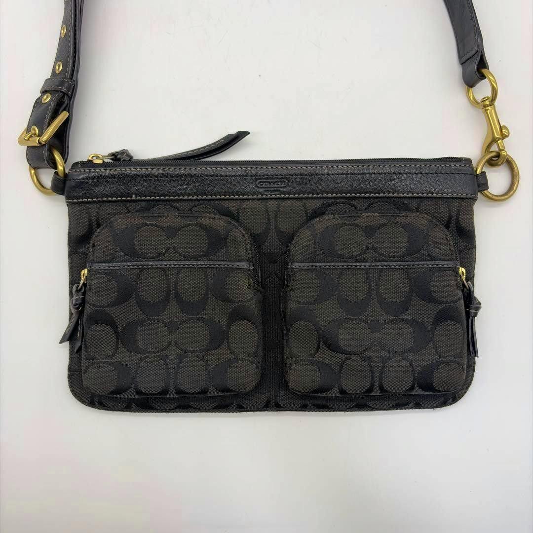 Front view of the black Coach canvas shoulder bag with signature C pattern and two front zip pockets.