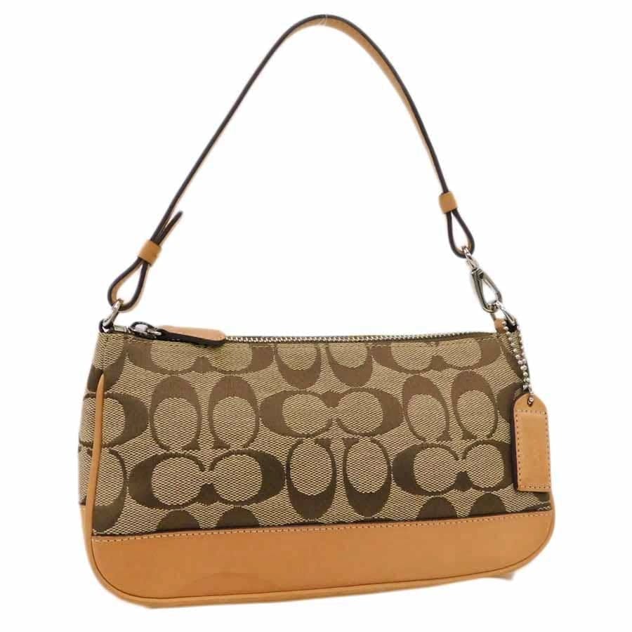 Brown Coach signature canvas accessory pouch with leather trim and short strap on white background.