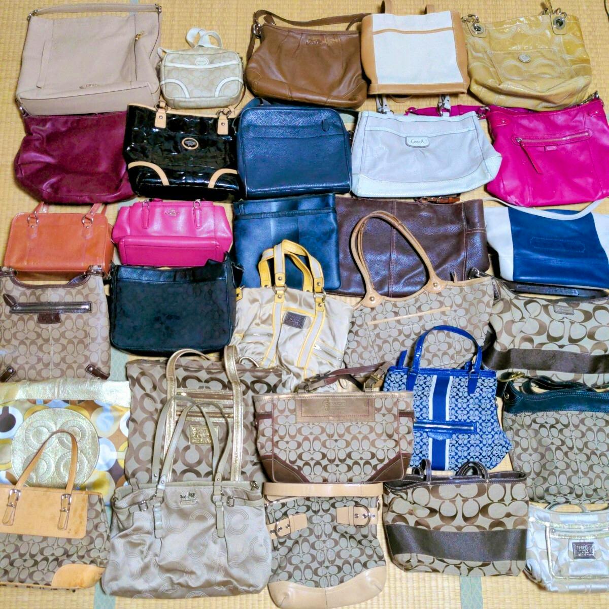 Top-down photo showing numerous COACH canvas and leather handbags and totes arranged on a tatami mat floor as a bulk lot.