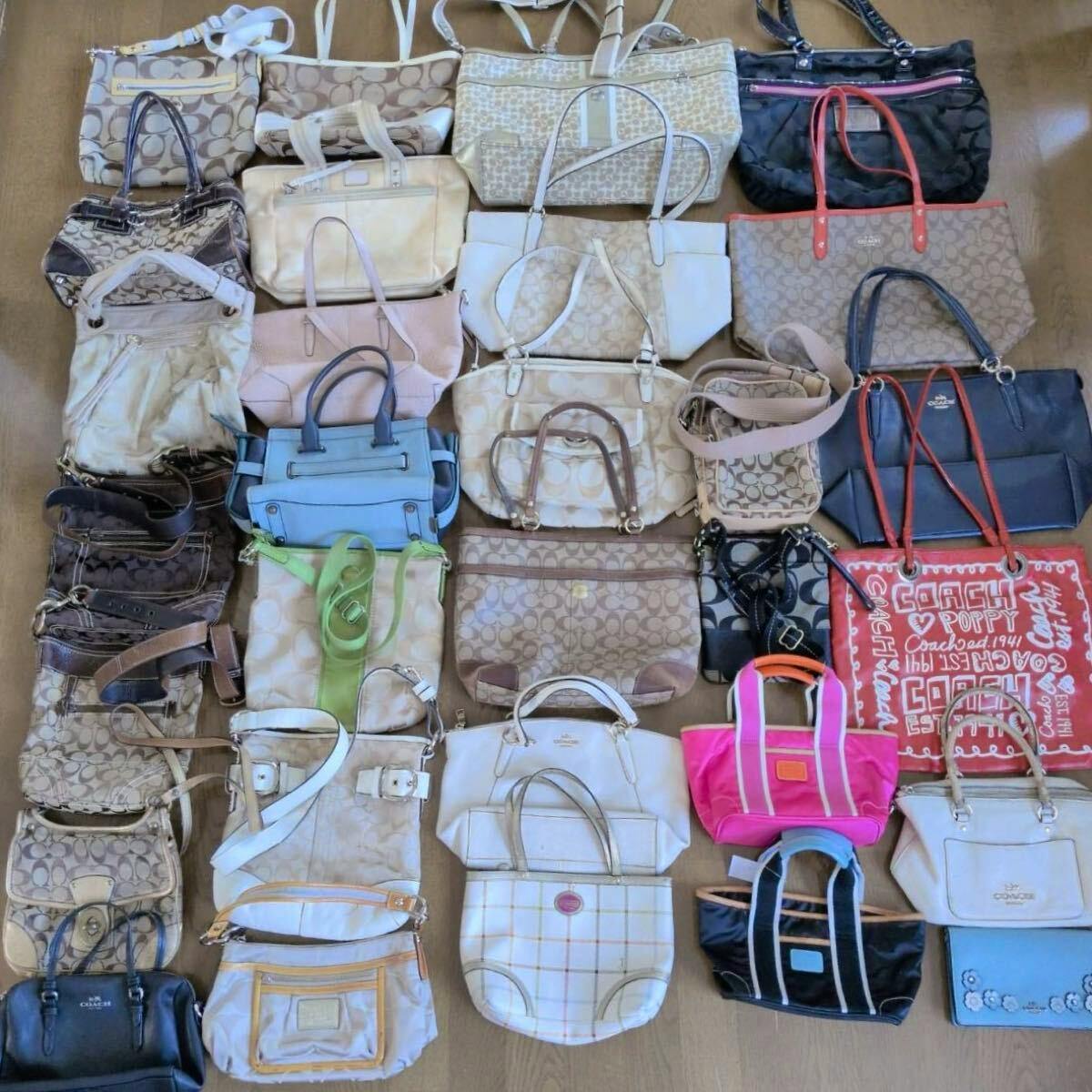 Top-down photo of many Coach canvas and leather handbags and totes laid out on a floor.
