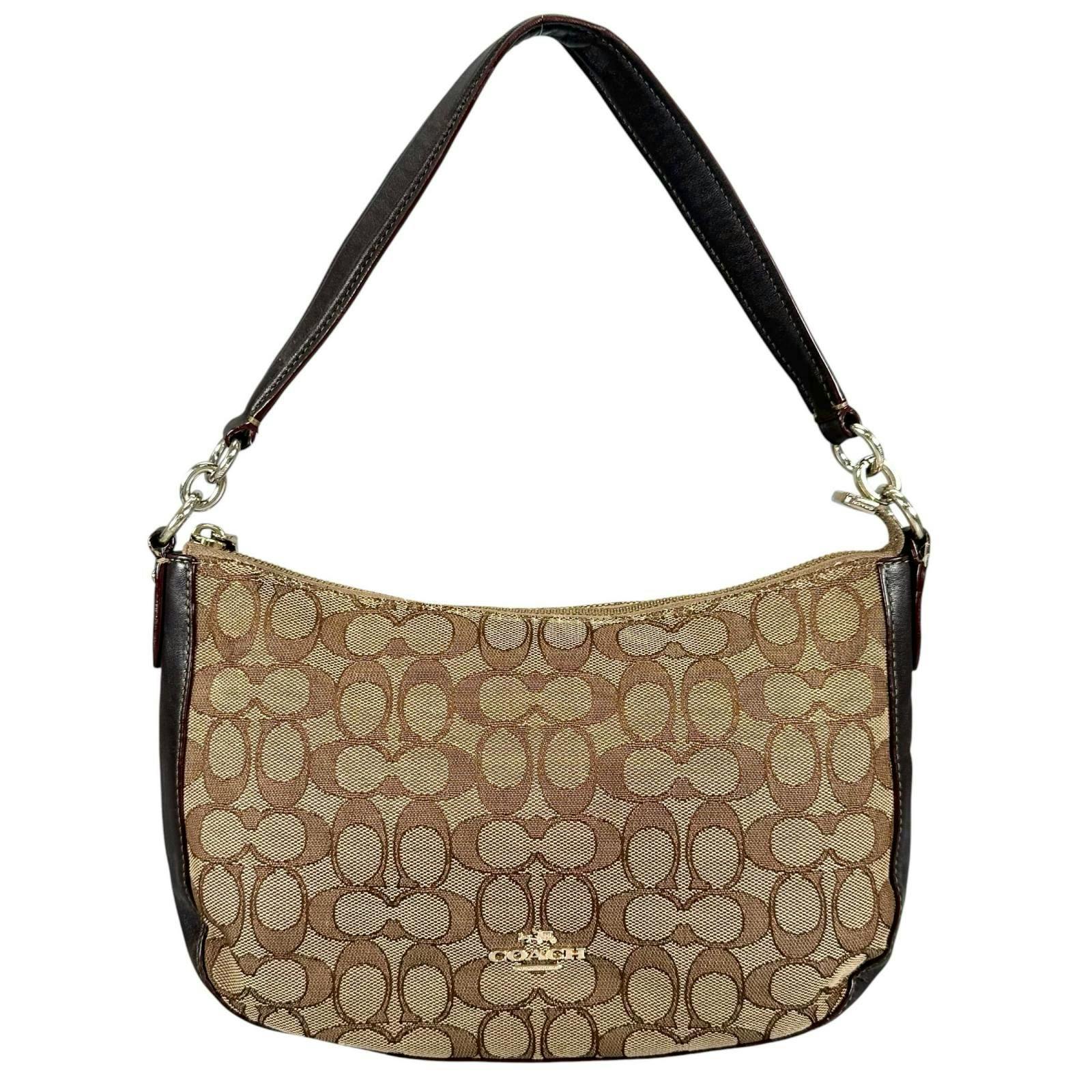 Front view of a brown Coach canvas and leather women's signature-pattern handbag with a single shoulder strap and visible logo.