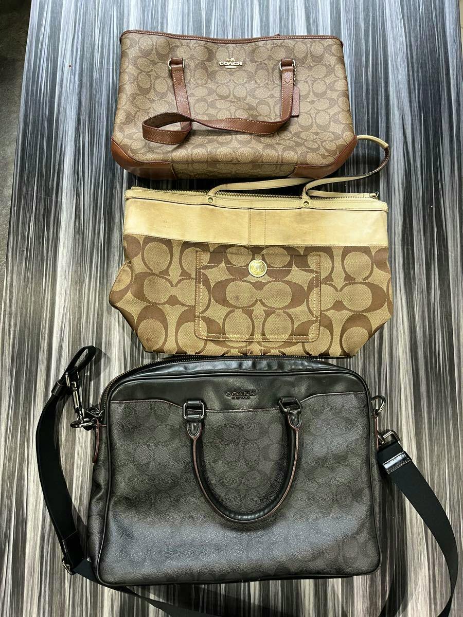 Three COACH signature canvas and leather bags stacked on a striped surface.