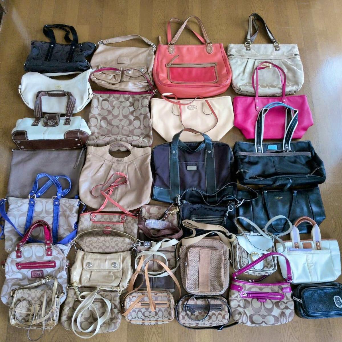 A large assortment of COACH handbags and small bags arranged on a wooden floor in a grouped set.