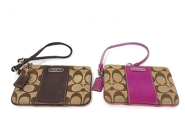 Two COACH signature canvas and leather wristlet pouches, one brown and one pink, shown flat on a white background.
