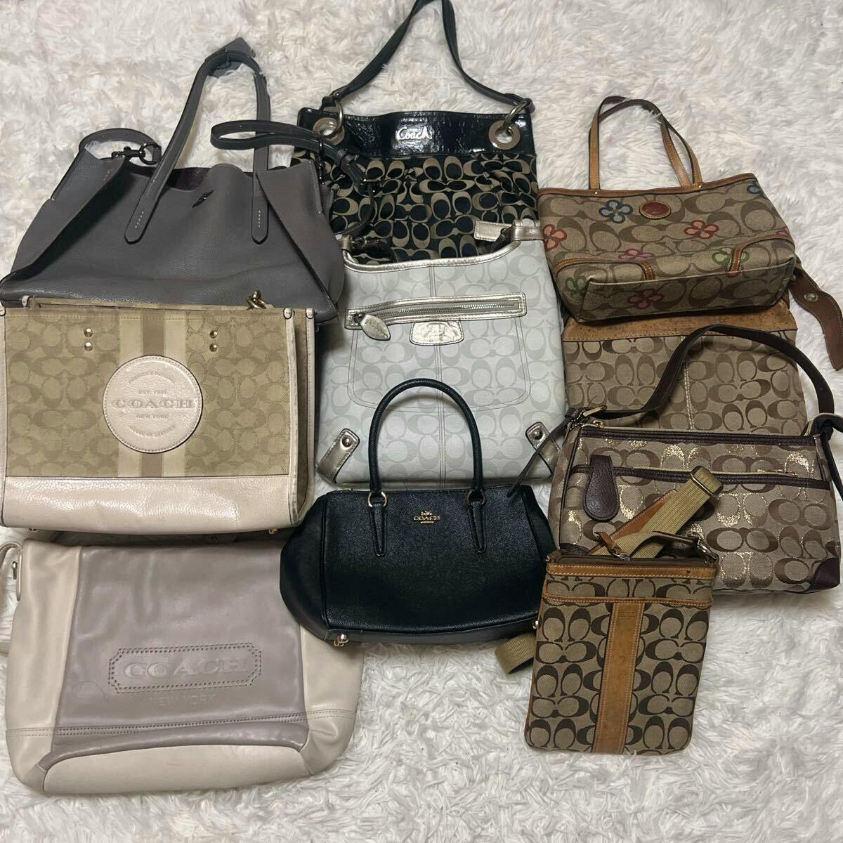 Multiple COACH handbags and shoulder bags with signature C patterns and leather details arranged on a white rug.